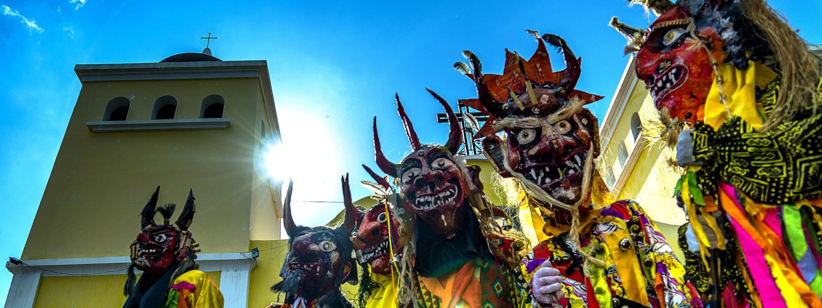 A group of people wearing grotesque festival masks