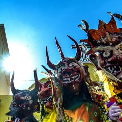 A group of people wearing grotesque festival masks