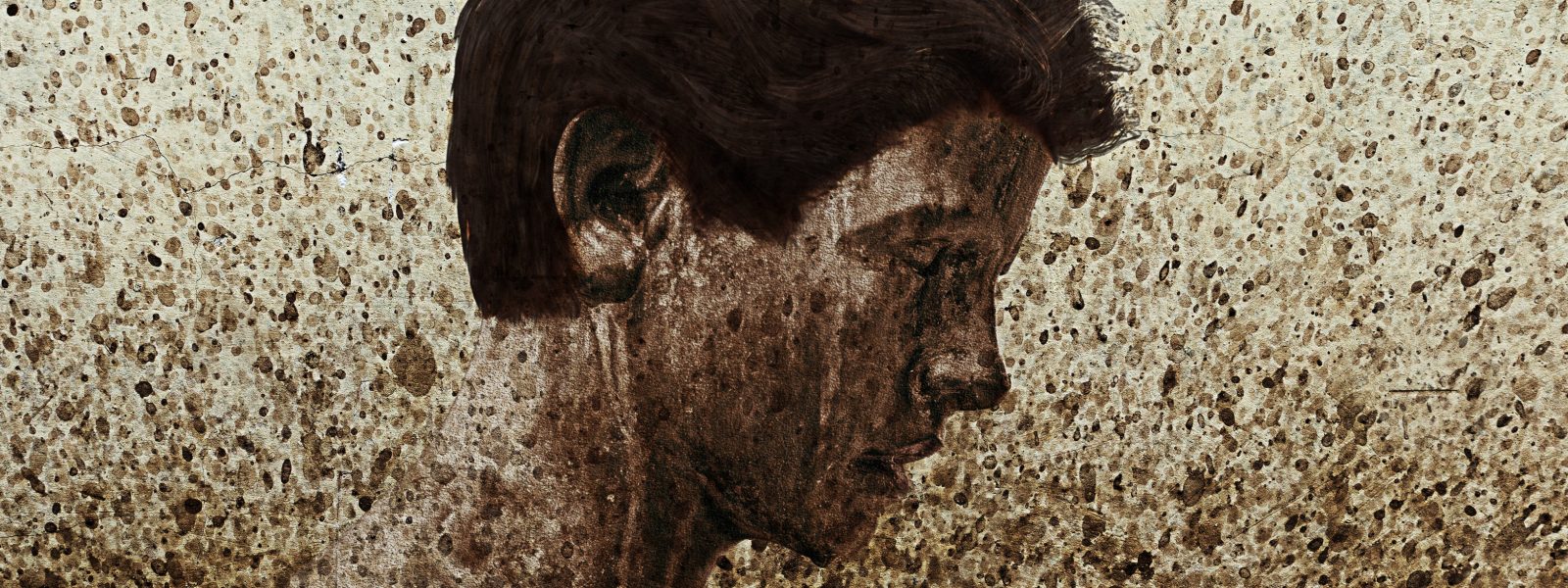 image of a dark haired boy's head in profile, overlaid with flecks of mud