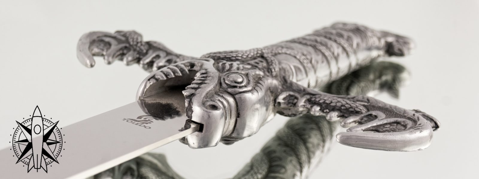 a sword hilt with dragon embellishments reflected on a mirrored surface