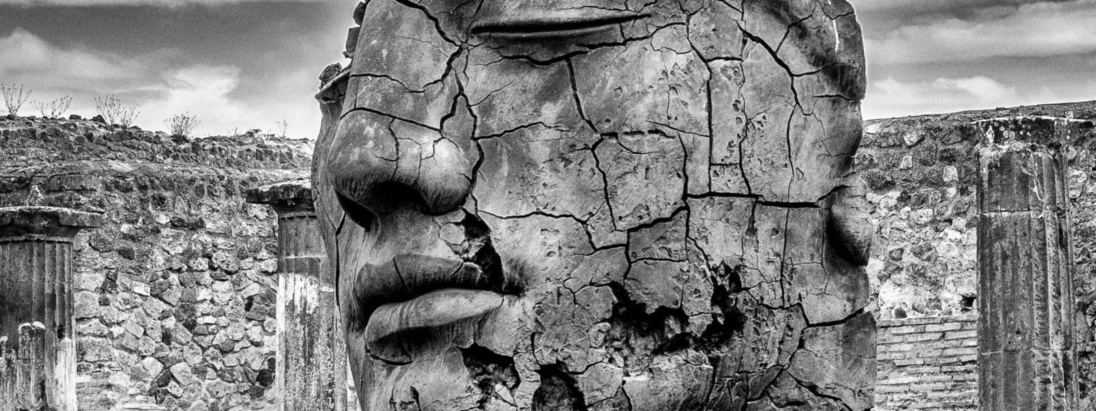 a greyscale image of a ruined stone head